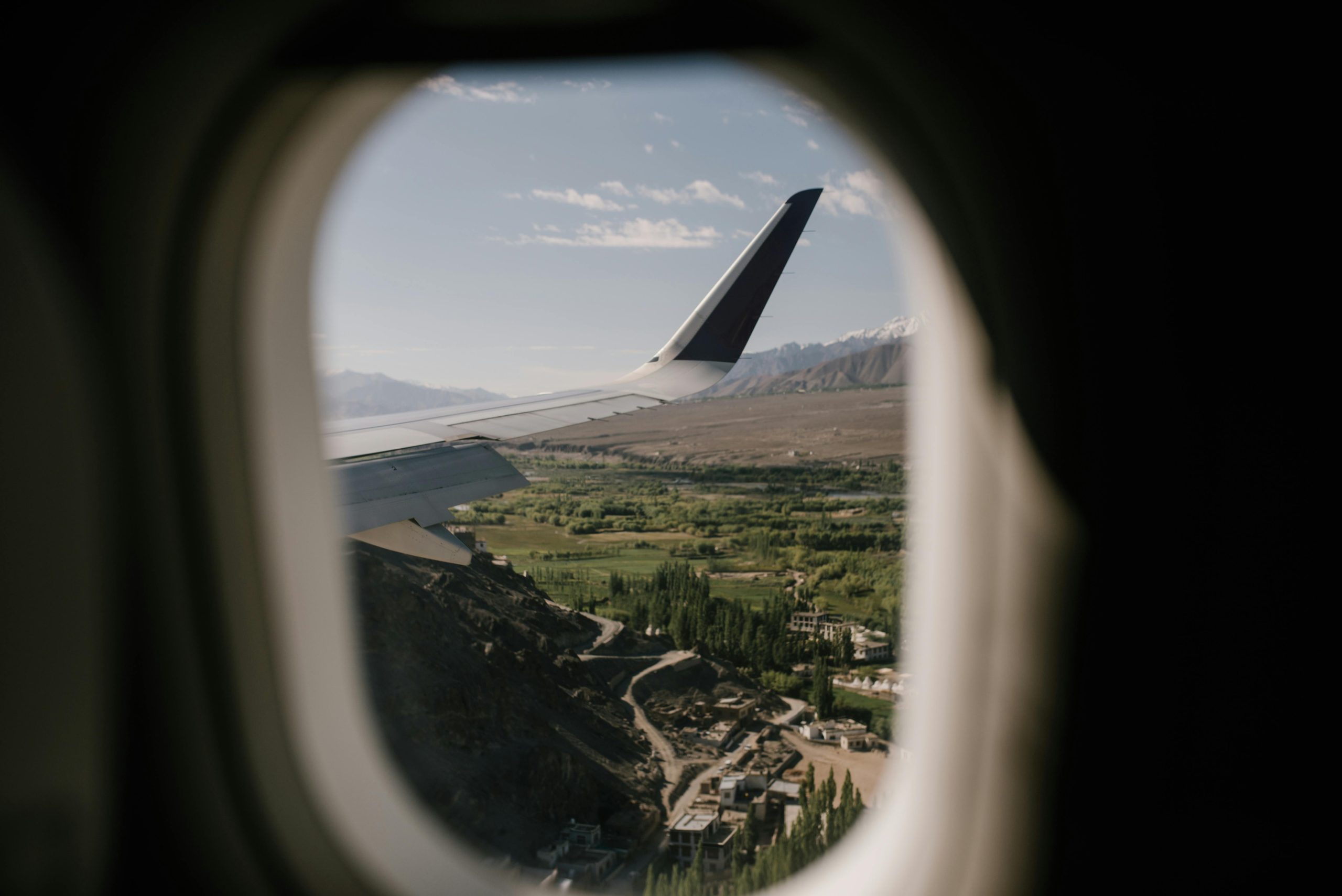 Scenic view of green landscape with mountains through an airplane window, showcasing travel adventure.